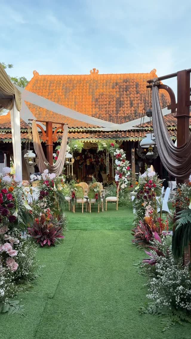 Colorful floral arrangements lining a green grass aisle leading to a wedding altar.
