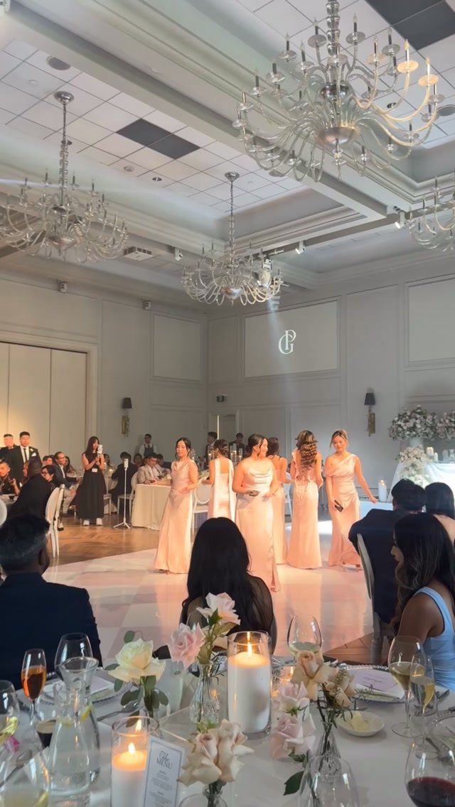 Bridesmaids in pink dresses dancing on a ballroom floor during a wedding reception.