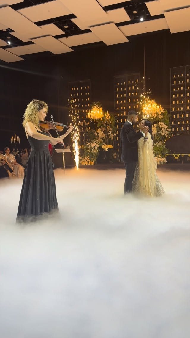 Bride and groom dancing in white fog while a violinist plays nearby