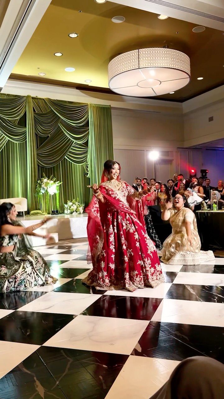 Woman in red bridal lehenga dancing on a checkered floor at a wedding reception