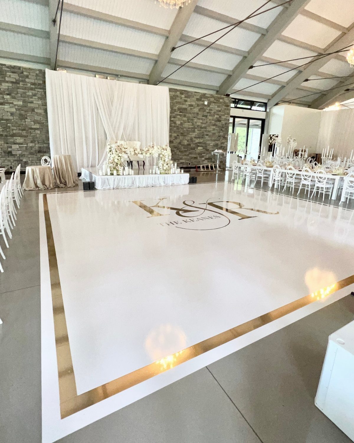 White glossy dance floor with gold monogram and border in a wedding venue