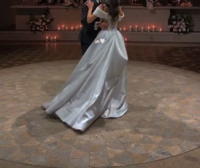 Bride and groom dancing together on a circular floor with candles in background