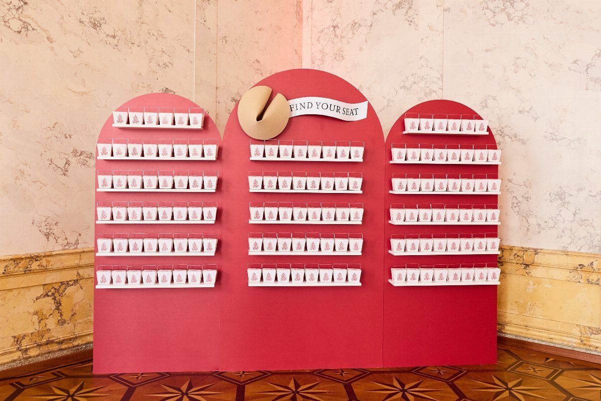 Red arched seating chart display with white name cards and find your seat sign.
