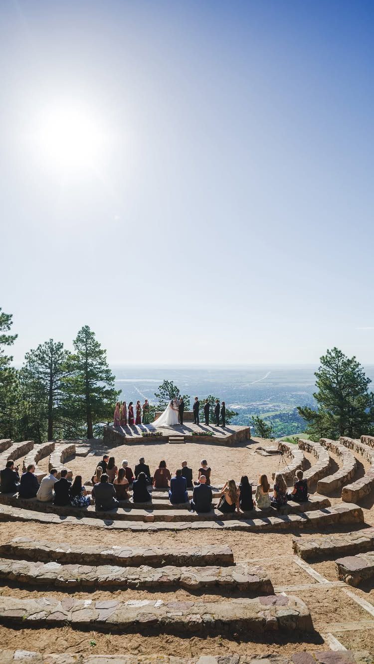 Wedding ceremony in a stone amphitheater with guests seated in curved tiers.