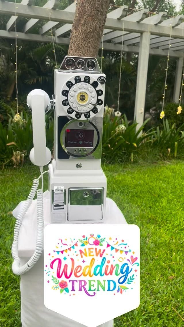 Vintage white rotary phone audio guestbook on a table in a garden setting.