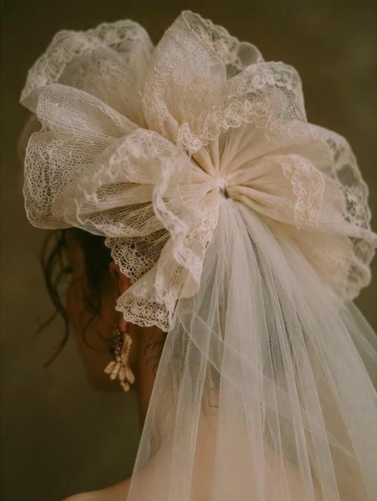 Ivory lace sculptural bow headpiece with a sheer tulle veil on a bride