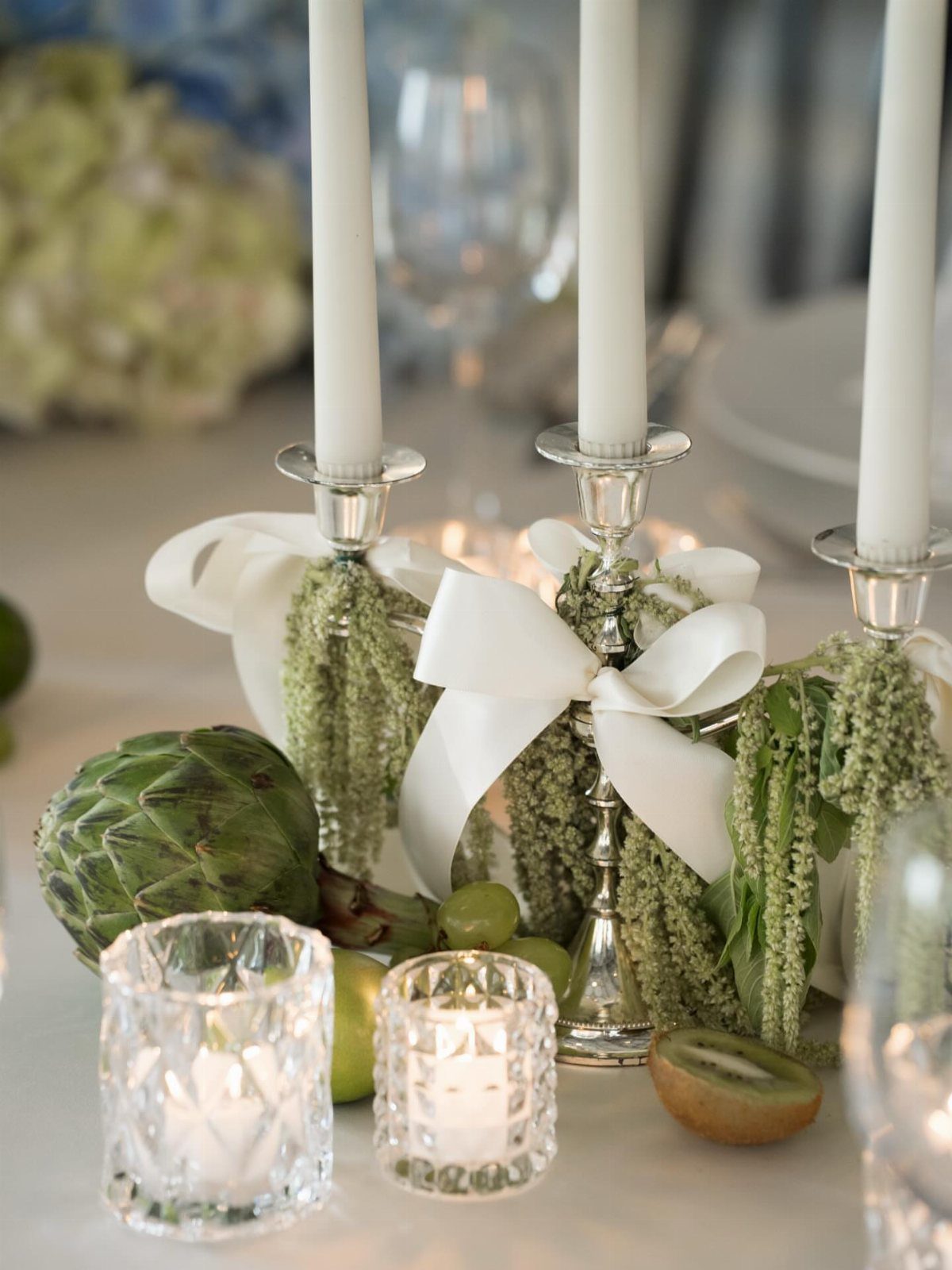 Silver candelabra with white candles and green foliage on a luxury table setting