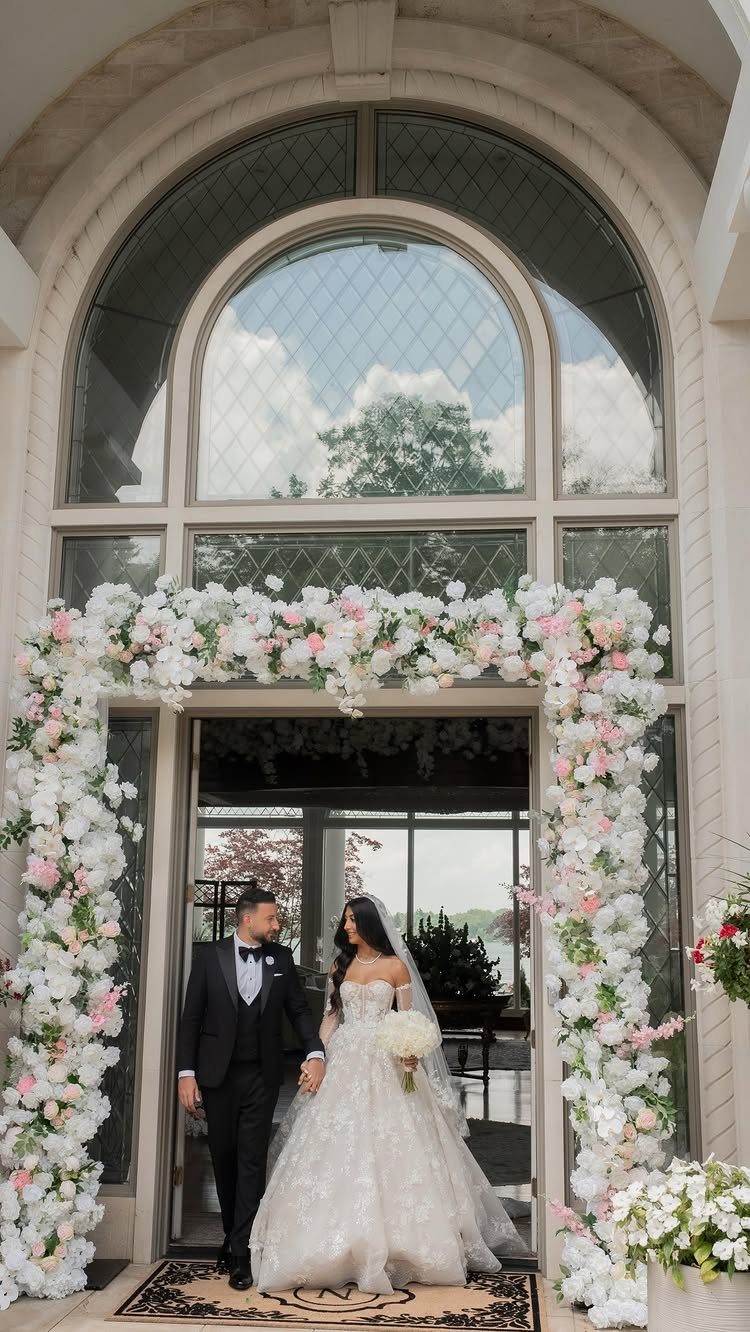 Bride and groom walking through a floral archway during their wedding exit.