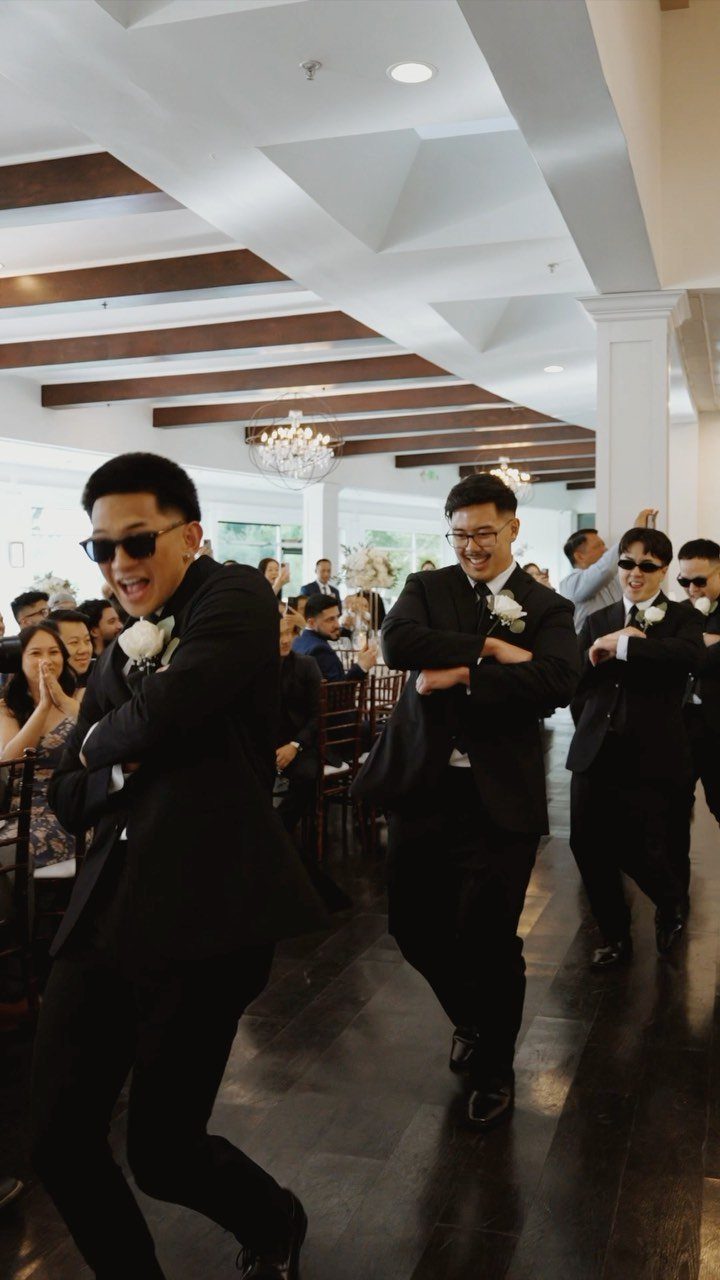 Three men in black tuxedos dancing during a wedding reception entrance.