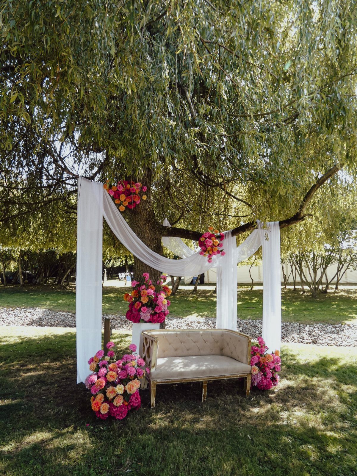 Weeping willow tree decorated with white fabric and pink flowers for a wedding