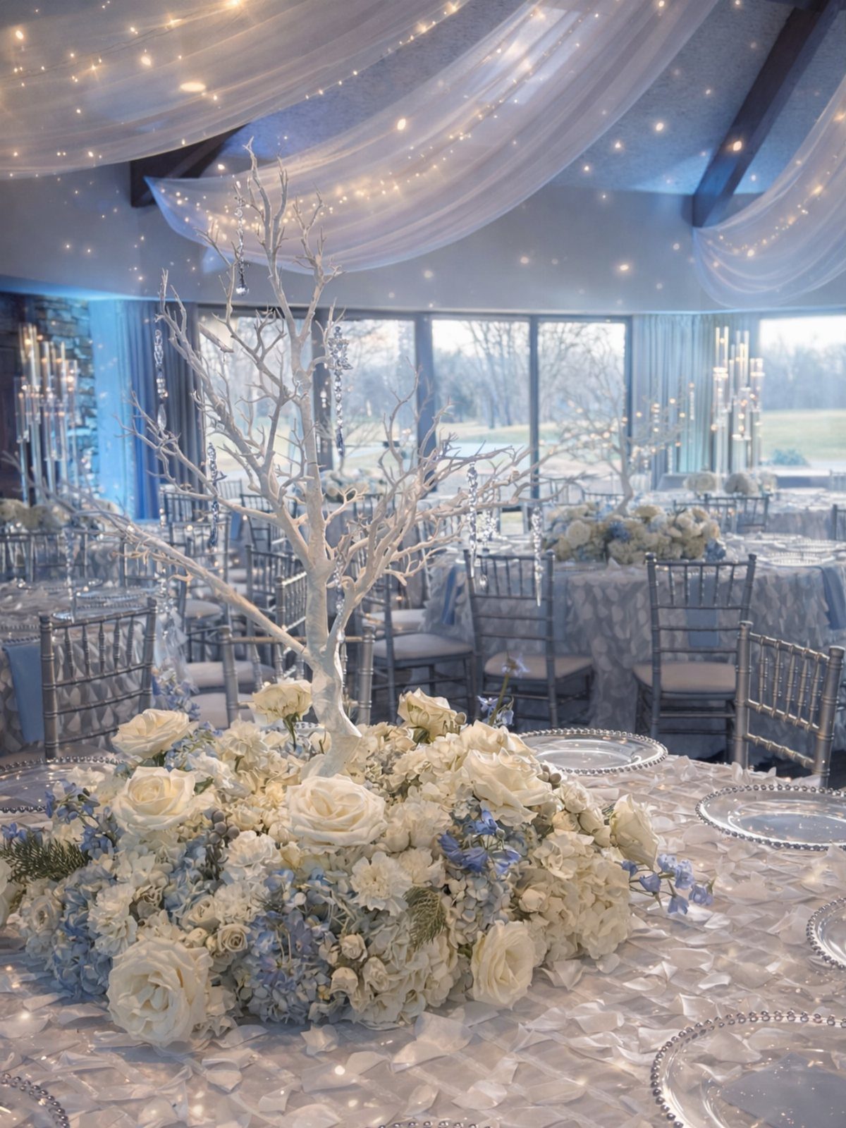 White floral centerpiece with a decorative white branch tree on a wedding table.